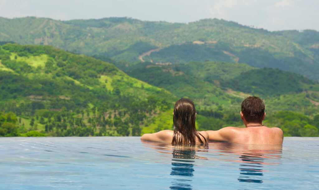 Couple dans une piscine admirant les montagnes verdoyantes