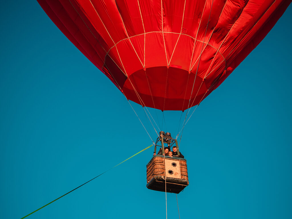 Un couple et un enfant en montgolfière rouge dans le ciel