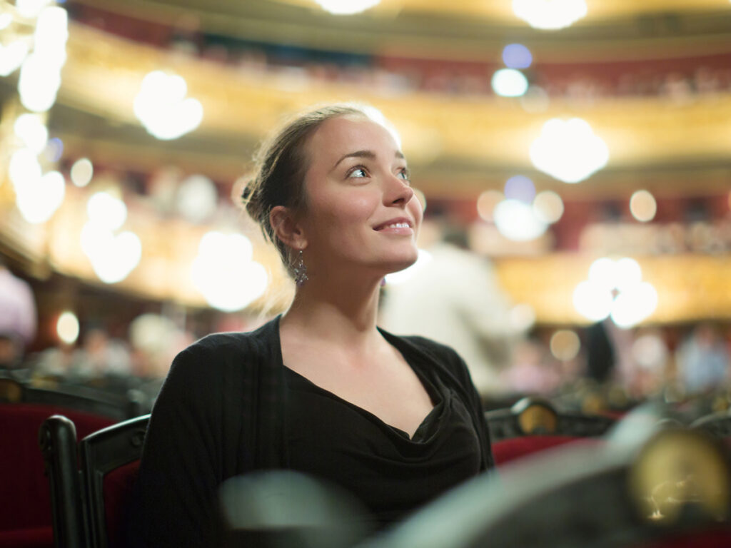 Femme souriante assise dans une salle d’opéra