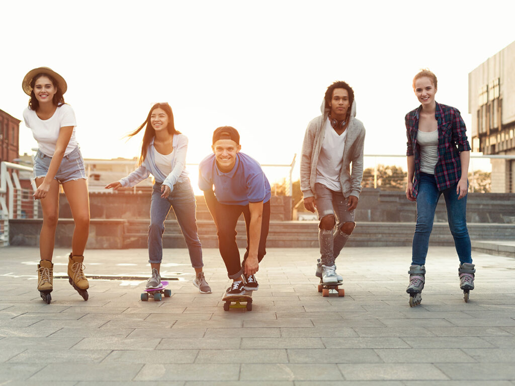 Groupe d’adolescents souriants en skateboard et rollers