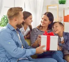 Une femme reçoit une grande boîte de cadeaux de son mari et de ses enfants à l'occasion de noël.