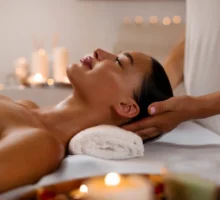 Femme détendue recevant un massage de la tête pour la fête des mères par un masseur professionnel, se reposant dans un spa moderne de luxe dans une atmosphère calme et sereine, vue de côté.