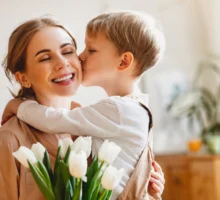 Un fils embrasse sa mère heureuse et lui donne un bouquet de tulipes à l'occasion de la fête des mères lors d'une célébration à la maison.