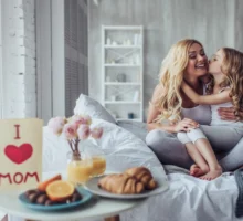 Une jeune femme et une petite fille mignonne passent du temps ensemble à la maison, assises sur le lit. Petit déjeuner au lit pour la fête des mères.