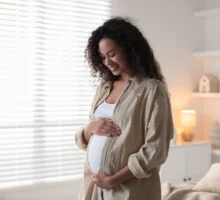 Portrait d'une belle femme enceinte près d'une fenêtre à la maison.