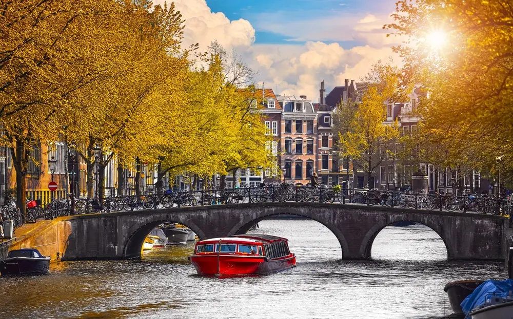 Canal à Amsterdam Pays-Bas Hollande maisons sous la rivière Amstel. Bateau de plaisance sous le pont. Point d'intérêt vieille ville européenne paysage printanier avec soleil.