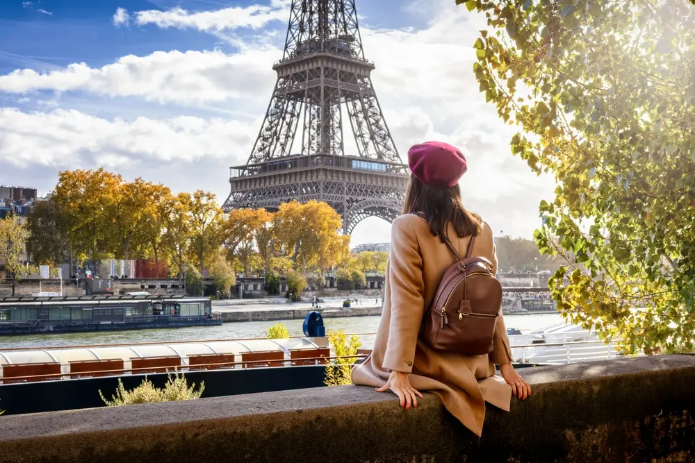 Une touriste avec un béret qui se trouve au bord de la Seine et jouit d'une belle vue sur la Tour Eiffel à Paris, France
