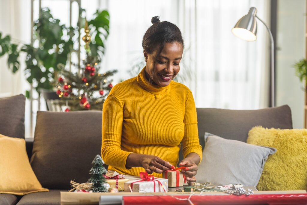 Mujer sonriente envolviendo regalos de Navidad