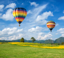 Dos globos volando sobre campo verde en día soleado