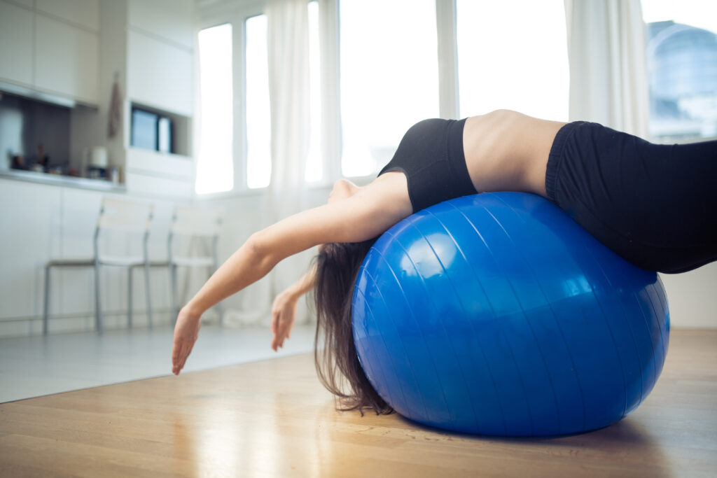 Mujer praticando pilates en casa con pelota de fitness