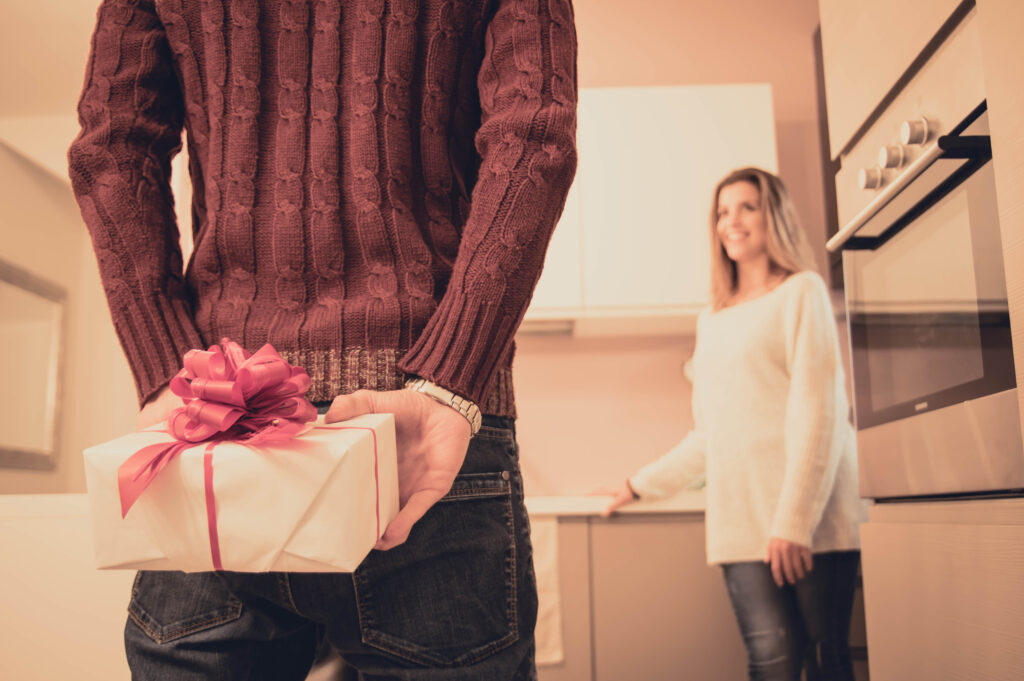 Hombre escondiendo regalo para su novia