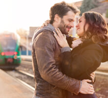 Pareja feliz se abraza en estación de tren