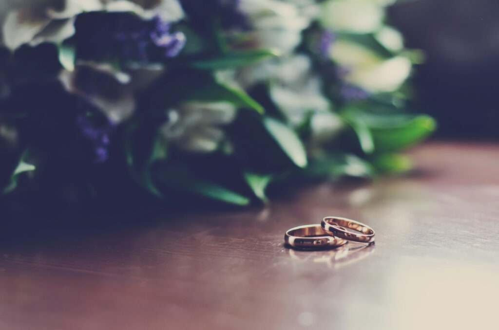 Fotografía de anillos de boda en una mesa con flores