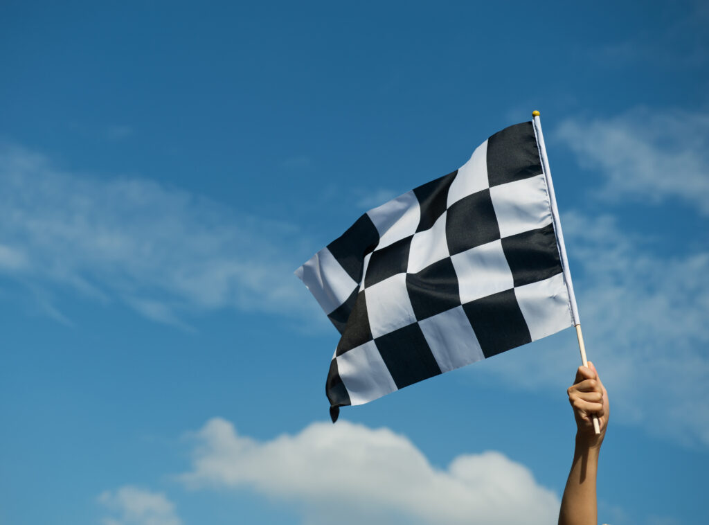 Brazo agitando una bandera de carrera de coches