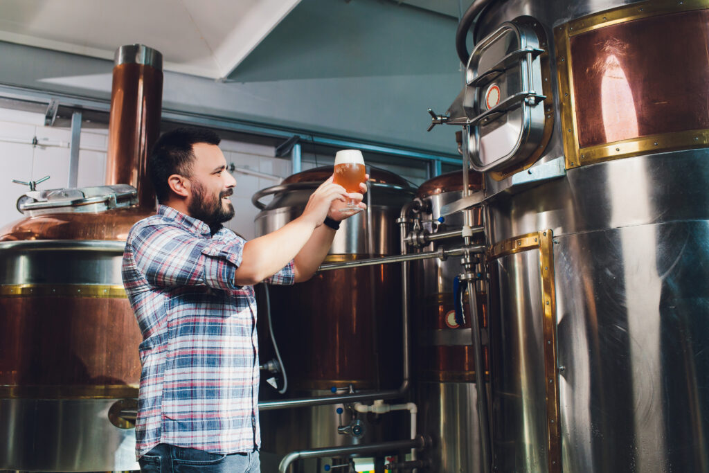 Hombre sonriente sosteniendo una cerveza en una fábrica