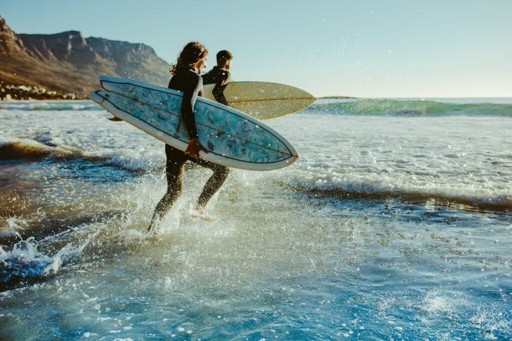 Dos personas entrando en el mar para realizar surf