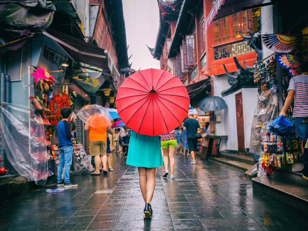 Mujer caminando en chinatown con un paraguas con la bandera de China