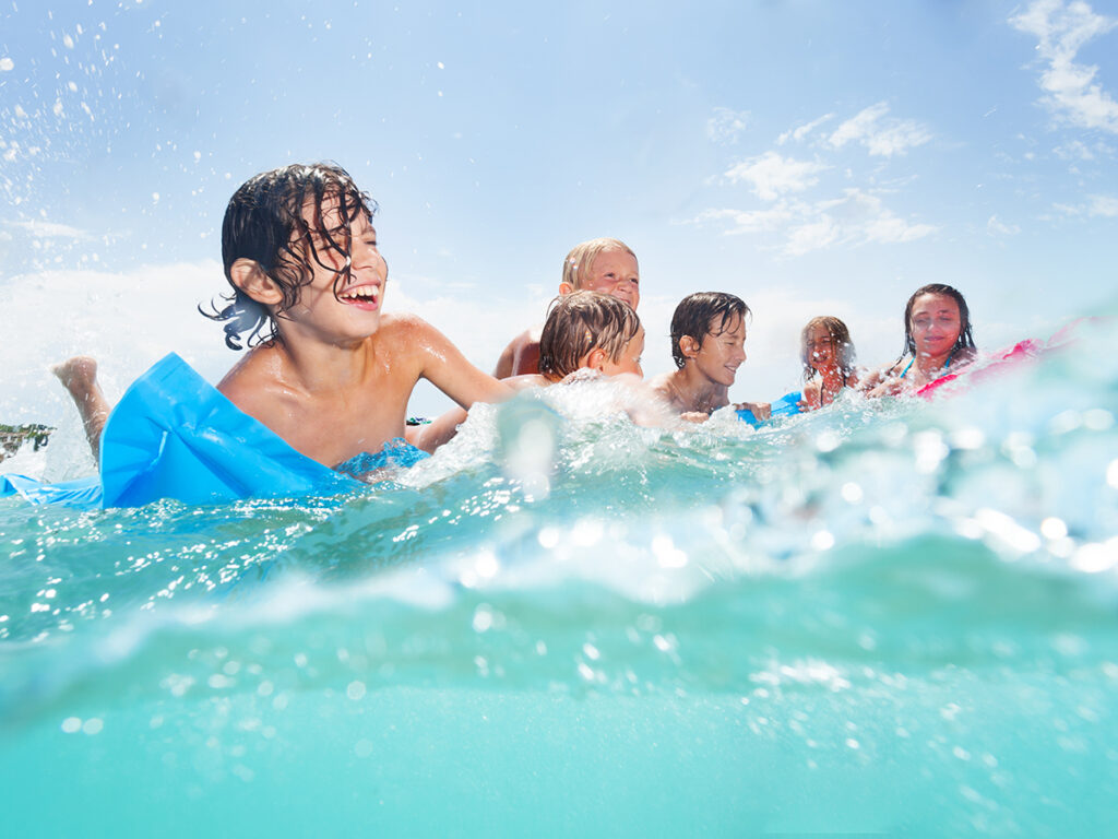 Niños felices jugando con las olas del mar