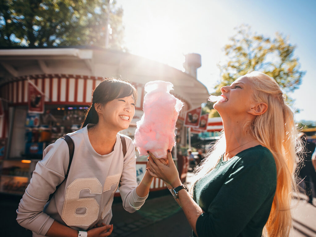 Chicas jóvenes comiendo algodón de azúcar en un parque de atracciones