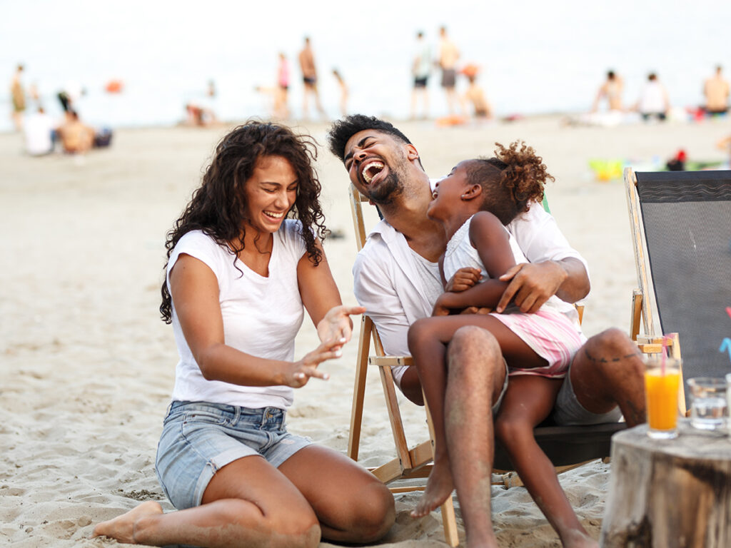 Familia riendo sentados en la playa