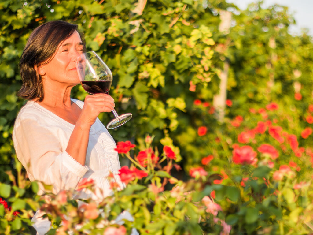 Una mujer degustación una copa de vino tinto en un viñedo