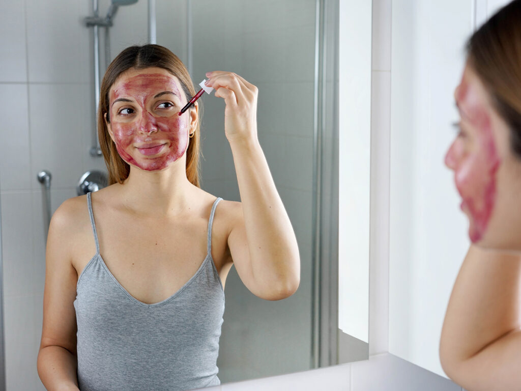 Mujer aplicándose exfoliante químico en la cara en el baño