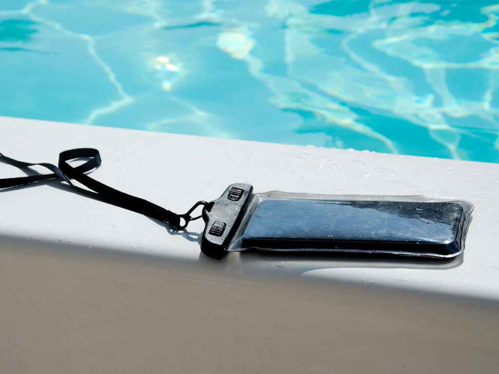Móvil con funda resistente al agua en el borde de una piscina