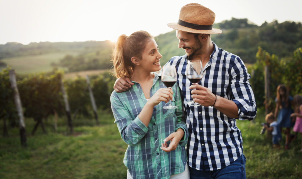 Un couple tenant des verres de vin dans les vignes