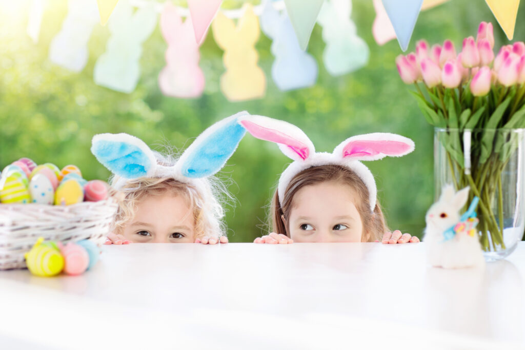Deux petites filles regardant au-dessus de la table avec un panier de chocolats de Pâques