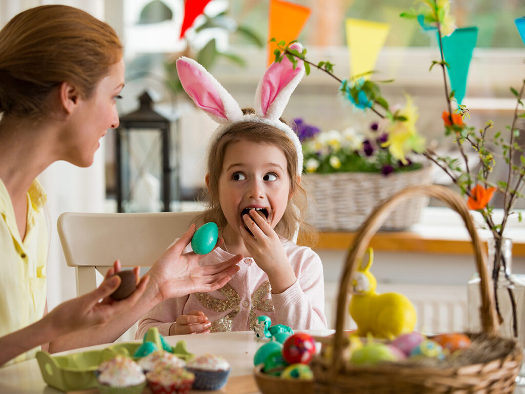 Mère et fille fêtant Pâques, mangeant des œufs au chocolat.