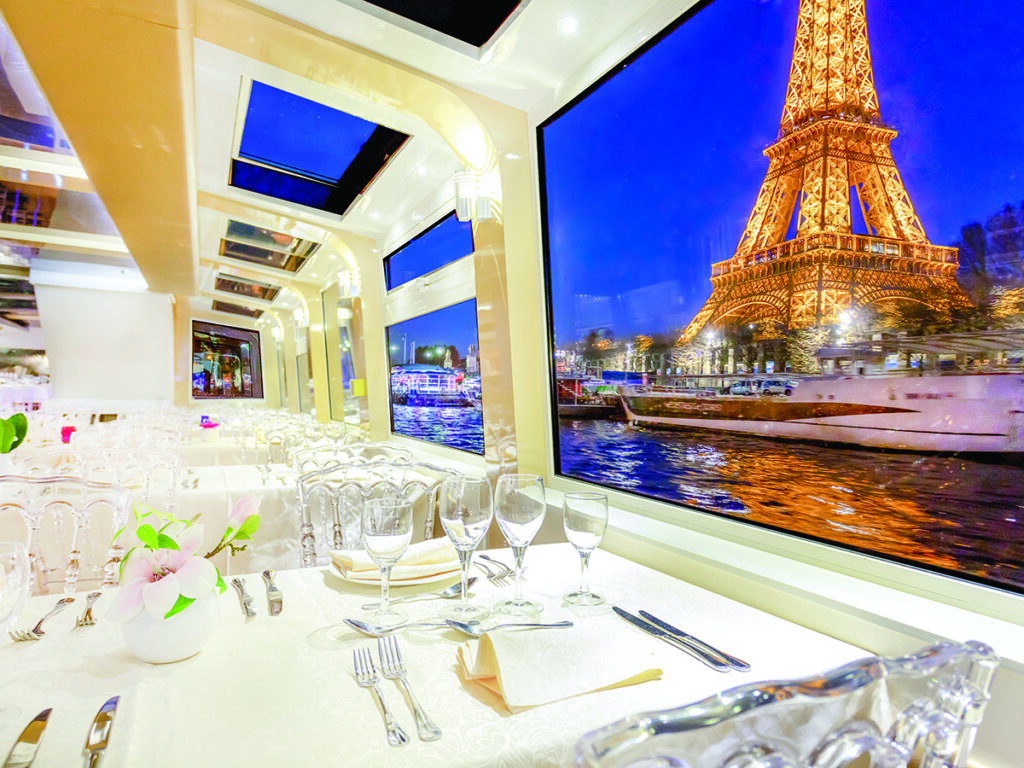 ntérieur élégant du restaurant d’un bateau-mouche avec vue sur la Tour Eiffel illuminée